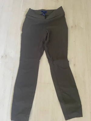 Grå leggings byxor från APT.9 Brynn - Snygga grå leggings från APT.9 Brynn med hög midja och smal passform. Tillverkade i mjukt material med 80% rayon, 17% nylon och 3% spandex för extra stretch och komfort. Perfekta för en avslappnad och trendig look.  material Rayon Nylon Kragtiga leggings med bred resår över magen 