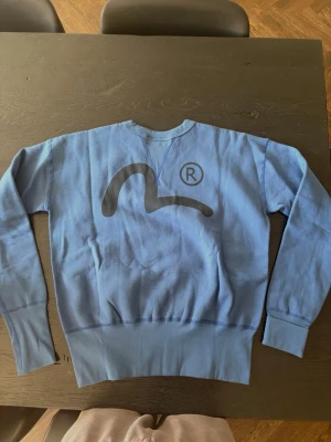 Blå Evisu tröja  - Säljer en blå vintage Evisu Hidehiko Yamane tröja Perfekt för dig som gillar streetwear och unika plagg. Aldrig använt.