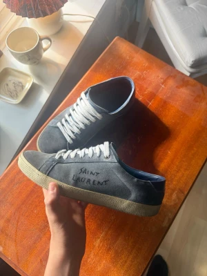 Blå/gråa Saint Laurent sneakers i mocka - Ett par unika Saint Laurent skor i färgen blå/grå som nu inte längre görs till och med. Jag säljer dessa till ett bra pris eller även intresserad inom byten mot till exempel maison margiela gata. Hör gärna av er vid bytes förslag, prisförslag eller frågor!😀✅🇮🇹