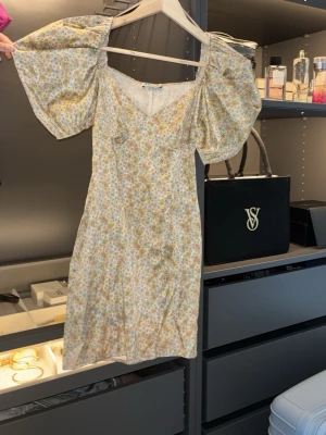 Blommig kortklänning med puffärm från Zara - Supersöt kortklänning med småblommigt mönster i ljusa färger. Klänningen har v-ringning och stora puffärmar som ger en trendig look. Perfekt för sommarens alla tillfällen och har en feminin passform.