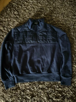 RLX Ralph Lauren  - Mörkblå RLX Ralph Lauren quarter zip med quiltad detalj över bröstet. Storlek S