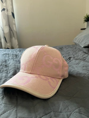 Ljusrosa keps - Snygg ljusrosa keps. Kepsen har böjd skärm och är tillverkad i ett strukturerat tyg med vit kant runt skärmen. Perfekt accessoar för en trendig och avslappnad look.