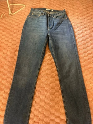 Klassiska blå raka jeans - Ett par klassiska blå jeans med rak passform och fem fickor. Jeansen har normal midja och stängs med dragkedja och knapp. Materialet är denim i bomull och de har en tidlös look som funkar till det mesta.