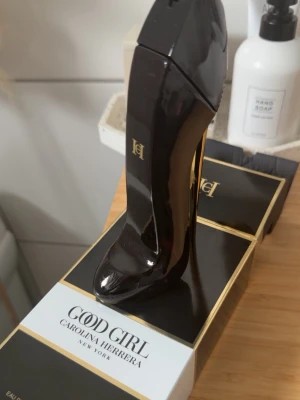 Good Girl parfym högklackad flaska - Good Girl från Carolina Herrera i en unik flaska formad som en svart högklackad sko med gulddetaljer. Parfymen har en lyxig och elegant design som sticker ut på hyllan. Perfekt för dig som gillar snygga och kreativa parfymflaskor.