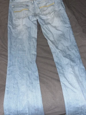 Ljusblå jeans Doris med gul söm - Ljusblå jeans från Doris med raka ben och snygga guldfärgade sömmar på bakfickorna. Klassisk femficksmodell i denim, perfekt för dig som gillar en avslappnad och tidlös look. Materialet är bomullsdenim som känns bekvämt hela dagen.