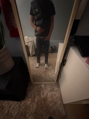 Svart dunväst med hög krage - Snygg svart dunväst med hög krage och quiltad design. Västen har en klassisk passform och stängs med dragkedja framtill. Perfekt att slänga över en hoodie eller t-shirt för en chill och trendig look.