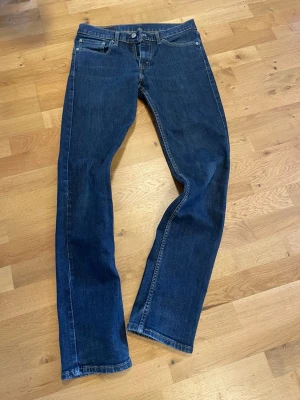 Mörkblå raka Levi's jeans - Klassiska mörkblå jeans från Levi's med rak passform och fem fickor. Jeansen har en tidlös look med kontrastsömmar och Levi's ikoniska läderpatch bak i midjan. Tillverkade i slitstark denim som passar perfekt till alla tillfällen.