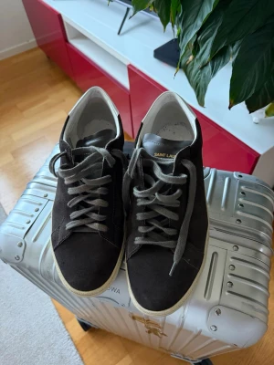 Saint Laurent sneakers  - Bruna sneakers från Saint Laurent i mocka. Låg modell med vit sula. Nästan helt nya men några år gamla så limmet har släppt något på höger sko, se bild.
