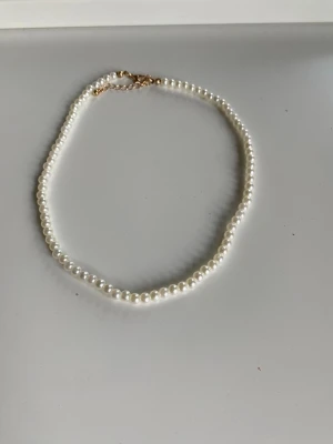 Pärlhalsband - Säljer ett halsband med vita pärlor och du kan välja om halsbandet ska sitta högt upp eller lite längre ner