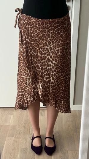 Leopardmönstrad omlottkjol med knyt - Snygg omlottkjol med leopardmönster i bruna och beige toner. Kjolen har knyt i midjan och en lätt volangkant nertill🤍🐆