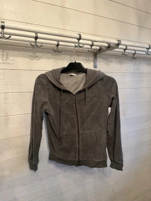 Grå zip hoodie i mjukt tyg XS - Säljer en enkel och stilren grå hoodie med dragkedja framtill och två fickor. Hoodien har huva med snören och är gjord i ett mjukt, bekvämt material. Perfekt för chill dagar eller när du vill ha något casual och skönt.
