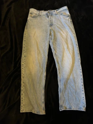 Ljusblå raka Jack & Jones jeans - Säljer ett par ljusblå Jack & Jones jeans med rak passform och klassisk femficksdesign. Jeansen har hög midja och är tillverkade i denim med en snygg tvättad look. Perfekta för en avslappnad och trendig stil.