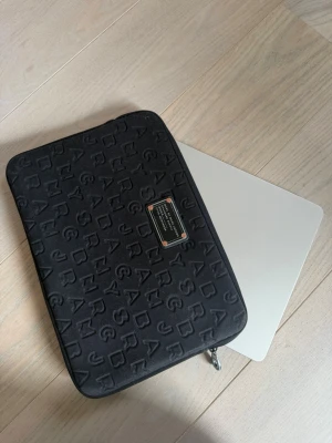 Svart datorfodral Marc Jacobs  - Snyggt svart datorfodral från Marc Jacobs för 13 tum dator. I bra skick, tappat lite silverfärg runt logga vilket syns på bilderna 