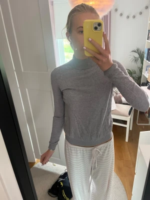 Grå tunn polotröja - Säljer en enkel och stilren grå polotröja med lång ärm. Tröjan är tunn och har ribbade muddar vid ärmslut och nederkant. Perfekt att matcha med jeans eller kjol för en clean look.