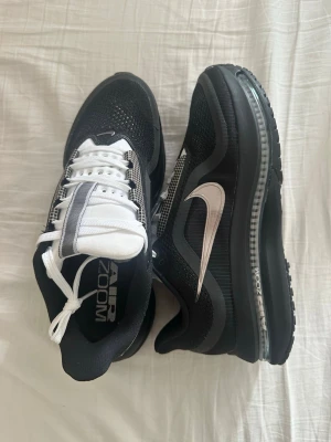 Nike Pegasus premium  - Nike i svart och vitt med mesh-ovandel och tydlig silverfärgad swoosh på sidan. Skorna har vita snören, svart sula med synlig Air Zoom-dämpning och detaljer i grått. Perfekta för dig som gillar sportig och modern stil. Använda några få gånger 