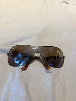 Bruna solglasögon - Snygga ray ban solglasögon med stora, bruna tonade glas och klassisk pilotform. Metallbågar i silver och smala skalmar med bruna detaljer. Perfekta för dig som vill ha en tidlös och cool look i solen.