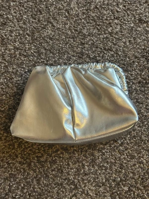 Silver clutch  - Snygg clutch i silver, endast använd en gång. Säljer den då den inte kommer till användning. Går att ha både med och utan kedja. Tror den är köpt på zalando. Skriv för fler bilder 💓