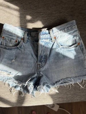 Ljusblå jeansshorts med fransar - Säljer ett par ljusblå jeansshorts från Levis modell 501, storlek S, blivit försmå o bara legat i garderoben. Använda nån gång. 