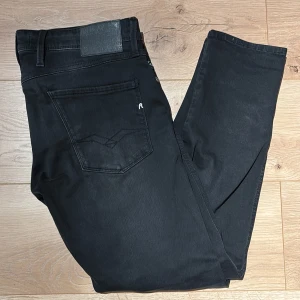 Replay Anbass svarta jeans, stl 33 - Replay Anbass jeans i svart – stilren modell med snygg passform och lätt tvättad finish. Klassisk femficksdesign med diskreta Replay-detaljer och en look som fungerar lika bra till skjorta som T-shirt.  Storlek: 33 Modell: Anbass Färg: Svart / mörkgrå Skick: Väldigt bra skick  Kommer från ett djur- och rökfritt hem och skickas snabbt, normalt samma dag. 📦