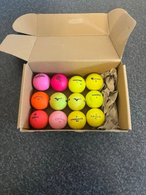 Färgglada golfbollar i mixade märken - Säljer ett set med tolv golfbollar i olika färger som rosa, gul och orange. Bollarna kommer från flera olika märken som Spalding, Wilson, Callaway och Pinetree. Perfekt för dig som vill ha synliga bollar på golfbanan. Levereras i kartong.