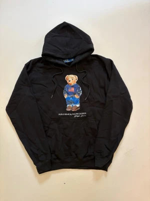 Ralph Lauren polo bear hoodie - Svart Ralph Lauren polo bear hoodie // 10/10 skick aldrig använd // storlek L // längd 66cm axelbredd 52cm armlängd 60cm // skriv vid minsta fråga eller fundering🤝