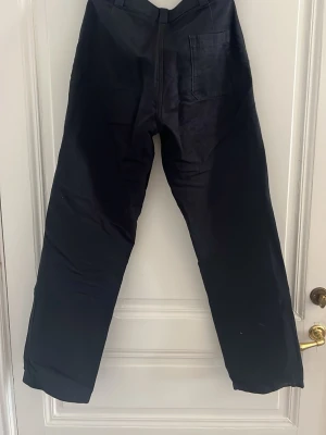 Svarta chinos med raka ben - Snygga mörkblå bomullsbyxor från Arket med raka ben och klassisk passform. Byxorna har en bakficka och diskreta framfickor. Tillverkade i ett mjukt tyg som ger en clean look. Perfekta för dig som gillar stilrena och enkla plagg.