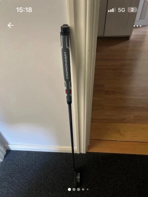 Golfputter Harmonized svart/grå vänster mycket bra  - Golfputter med svart och grått skaft och grepp där det står 'Harmonized'. Klubban har vita och röda detaljer på greppet och tydliga linjer på klubbhuvudet för sikte. Perfekt för dig som vill förbättra ditt närspel på greenen.