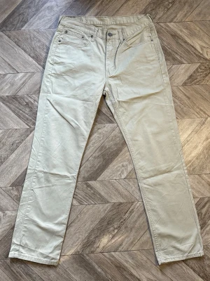 Levi's 514 - Snygga beiga jeans från Levi's med rak passform och klassisk femficksdesign. Byxorna har bälteshällor, knappgylf och subtila sömmar. Perfekta för dig som gillar en clean och stilren look.Längd 109cm Bredd 41cm