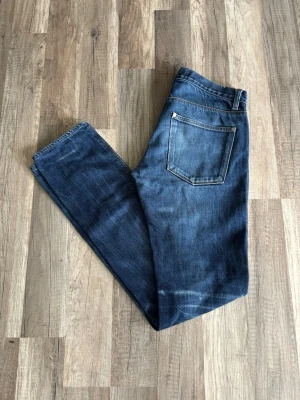 Mörkblå jeans från Acne Studios - Säljer ett par mörkblå jeans från Acne Studios med klassisk femficksmodell och raka ben. Jeansen har snygga slitningar och är tillverkade i ett mjukt denimtyg och är dry selvege. Perfekta för en avslappnad och trendig look.