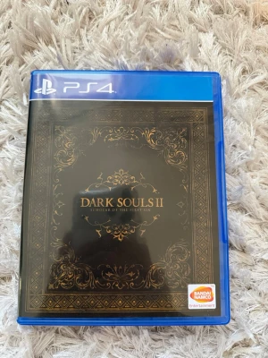Dark Souls II Scholar of the First Sin PS4 - Säljer Dark Souls II: Scholar of the First Sin till PS4. Spelet kommer i ett blått plastfodral med snyggt svart och guldigt omslag. Perfekt för dig som gillar utmanande action-RPG och mörk fantasyvärldar. Alla dlc