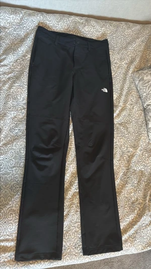 Svarta The North Face friluftsliv byxor  - Säljer ett par riktigt snygga och stilrena The North Face-byxor i svart. En clean och lättmatchad modell som passar perfekt till både vardagsoutfits, streetwear och en mer outdoor-inspirerad stil.  Byxorna har en modern och stilren passform med snygga detaljer och The North Face-loggan på benet. Den svarta färgen gör dem väldigt enkla att matcha med hoodie, t-shirt, jacka, sneakers eller boots. Byxorna är hela och fina utan några  skador, och detaljerna är i fint skick. 