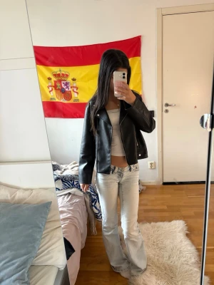 Svart skinnjacka med klassisk krage - Snygg svart skinnjacka med klassisk krage och dragkedja framtill. Jackan har en rak passform och stilrena detaljer som ger en cool look. Perfekt att matcha med jeans eller kjol för en trendig outfit.