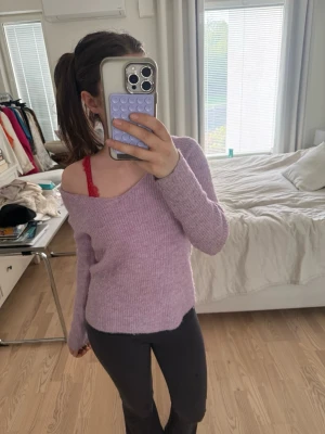 Ljuslila off shoulder stickad tröja - Superfin ljuslila stickad tröja med off shoulder-modell och långa ärmar. Tröjan har en mjuk och mysig känsla, perfekt för lager på lager. Passar dig som gillar en avslappnad men ändå trendig stil.