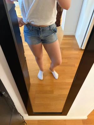 Blå jeansshorts med fransar - Säljer ett par klassiska blå jeansshorts med råa franskantade benslut och femficksmodell. Shortsen har normal passform och stängs med knapp och dragkedja. Perfekta till sommaren och lätta att matcha med olika toppar. MEN fram fickorna är ihåliga och finns slitage! Skriv pm vid funderingar!☺️