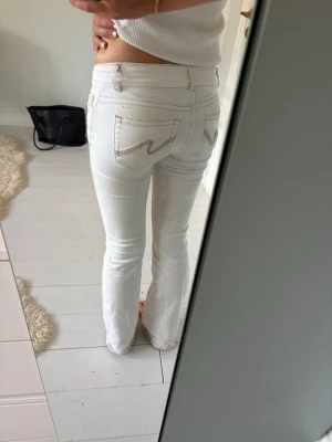 Vita bootcut jeans med kontrastsömmar - Säljer ett par vita, lågmidjade, bootcut jeans från Nelly med snygga kontrastsömmar och broderade bakfickor. Jeansen är inte tvättade på bilderna men fläckarna som syns har försvunnit nu när jag tvättat dem. 💕😅storlek 32/xxs men är stretchiga så passar även xs och s. 