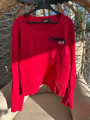 Sweatshirt Esprit strl. 38 - Röd sweatshirt från Esprit Sports med tryck på bröstet och rund halsringning. Tröjan har breda muddar vid ärmslut och nederkant, samt en avslappnad passform. 