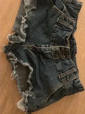 Mörkblå slitna jeansshorts - Jag säljer dessa snygga jeansshortsen från fantastic&forever info jeans med slitningar💕 de är i fint skick och bara använd 1 gång och är i storlek M💕 skriv vid minsta fundering💕