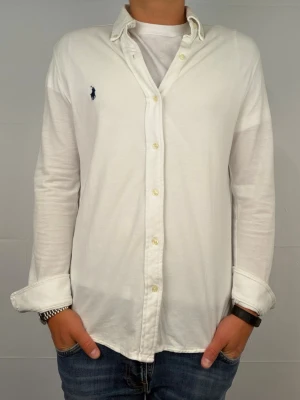 Ralph lauren skjorta S vit - Säljer denna fantastiskt snygga ralph lauren skjorta. Riktigt skönt material . Size S. Modellen är 180cm. Bredd 45cm längd 67cm! Fint skick, nytvättad och ny strykt så att skillnaden på denna och en ny ska vara minimal! Tyvärr är de ett litet hål där bak men de går att laga Fraktar samma dag som köp, kan gå ner i pris vid snabb affär! 🤩