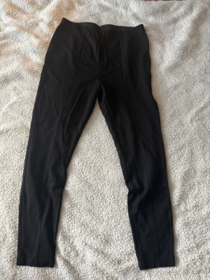 Svarta klassiska leggings - Ett par svarta, enkla leggings med hög midja och smal passform. De är helsvarta utan synliga detaljer eller mönster och har en stretchig känsla som gör dem bekväma att bära. Perfekta till en avslappnad stil eller att matcha med oversized tröjor. det är L men är lite i storleken passar dig som är M/S