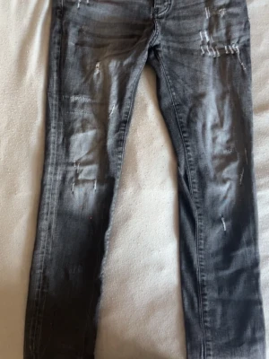 Gråa Dsquared2 skinny jeans S: M48 - Säljer ett par gråa Dsquared2 skinny jeans med slitningar och distressed detaljer på både fram- och baksida. Jeansen har klassisk femficksmodell och smal passform. Perfekta för en trendig och avslappnad look. Mycket bra skick taggen där back är lite sliten men inget man märker av. 