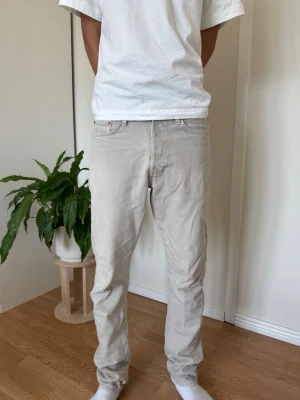 Beiga raka jeans - Säljer ett par stilrena beiga jeans med rak passform och klassisk femficksdesign. Jeansen har normal midja och är tillverkade i ett mjukt bomullstyg som känns skönt mot huden. Perfekta för dig som gillar en clean och enkel look.