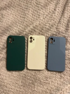 Tre oanvända iPhone 11 mobilskal i olika färger. Alla för 40 kr! - Säljer tre snygga mobilskal i färgerna mörkgrön, cremevit och ljusblå. Skalen har en slimmad design och är tillverkade i ett tåligt plastmaterial som skyddar mobilen mot repor och stötar. Perfekt för dig som vill variera stilen på din telefon.