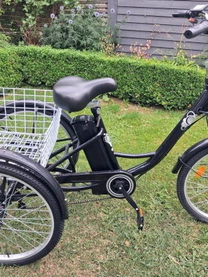 Svart eldriven trehjuling med korg - Säljer en svart eldriven trehjuling med stor vit metallkorg bak. Cykeln har bred sadel, lågt insteg och robust ram. Perfekt för dig som vill ha extra stabilitet och plats för packning. Utrustad med framlykta och reflexer.