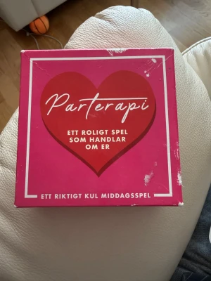 Parterapi sällskapsspel - Parterapi är ett roligt sällskapsspel för par eller grupper där man svarar på frågor om varandra. Spelet kommer i en fyrkantig, rosa kartong med ett stort rött hjärta på framsidan och innehåller 380 frågor. Perfekt för middagar och sociala tillfällen.