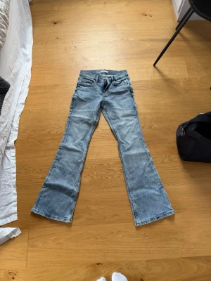 Bootcut jeans i ljusblå denim - Säljer ett par ljusblå bootcut jeans från Gina Tricot. Jeansen har klassisk femficksmodell, normal midja och utsvängda ben. Tillverkade i mjuk denim med snygg tvätt och slitningar för en avslappnad look.