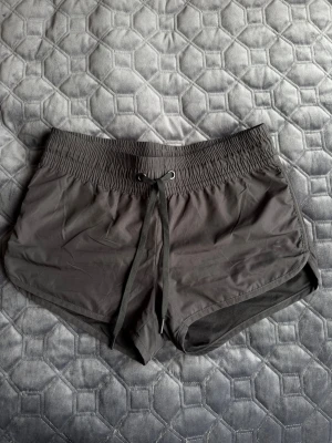 Svarta träningsshorts med snörning - Säljer ett par svarta träningsshorts med elastisk midja och snörning framtill. Perfekta för gymmet eller löprundan! Några sömmar har gått upp som ses på sista bilden, men gör inte att det är hål i byxorna