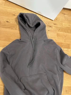 Grå hoodie från Zara - En stilren grå hoodie från Zara med klassisk känguruficka och justerbar huva med dragsko. Tillverkad i mjukt bomullsmaterial med borstad insida för extra komfort. Perfekt för en avslappnad och trendig look.
