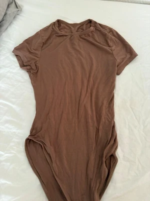 Brun basic kortärmad body - En enkel och stilren brun body med korta ärmar och rund hals. Tillverkad i mjukt och stretchigt material som sitter skönt mot kroppen. Perfekt att matcha med jeans eller kjol för en clean look.