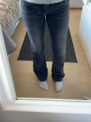 Svarta bootcut jeans med fickdetalj - Säljer ett par svarta bootcut jeans med snygg fickdetalj bak. Jeansen har klassisk femficksdesign och normalhög midja. Materialet är stretchigt och bekvämt, perfekt för en avslappnad stil.