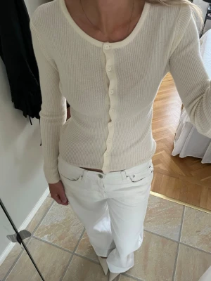 Ribbad cremevit kofta med knappar - Ribbad cremevit kofta med rund halsringning och långa ärmar. Storlek XS som på mig (S) gör att den sitter figurnära. I merinoull så kommer hålla länge om man tvättar rätt och tar hand om den! ❣️Har använt 1 gång. 